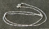 Sterling silver chain necklace laid out against a dark background to show clasp and link style