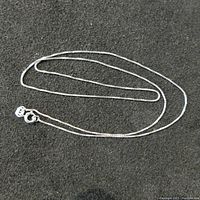 Sterling silver chain laid out on a dark surface showing the length and clasp.