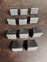 Photo showing 11 black silicone rubber floor protectors with grey felt pads on top, arranged in groups.