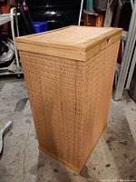 Full view of the laundry bin showing bamboo accents and woven rattan sides and lid from a standing angle.