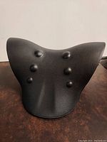 Top angled view of black foam traction device showing six raised nubs and contoured ergonomic shape.