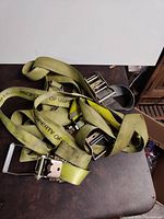 Photo of multiple green and yellow ratchet straps coiled together showing metal ratchets and accumulated use.