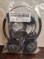 Factory sealed package showing black wired headset with padded ear cups, inline control, and USB connector.