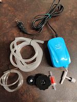 Blue MA-60 air pump with power cord, clear air tubes, black air stone, check valve, and T-valve.