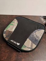 Top and side view of the portable foam seat cushion showing black center panel and camouflage print sides with Cabela's logo.