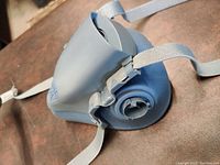 Side view of soft silicone respirator mask showing one filter port and adjustable straps.