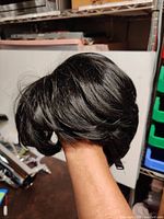 Wig shown from an angled side view showcasing the layered short style and shiny black hair fibers.