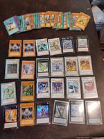 Overview photo showing a spread of 90 Yu-Gi-Oh cards arranged on a surface. The cards show a variety of monsters, spells, and traps with many holographic and foil effects visible.
