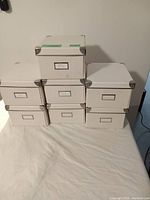 Stacked view of 7 white reinforced storage boxes showing label holders and metal corner protectors.
