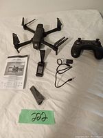 Complete ASC-2500 drone kit with drone, controller, battery, charging cable, instruction booklet, spare propellers, and charger base arranged on a flat surface.