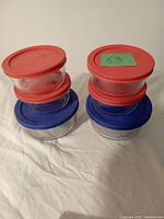 Photo showing six Pyrex glass containers with lids in two stacks.