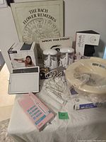 Wide view of health care items including posture wedge, Bach flower chart, Waterpik toothbrush handles, scale and others on table.
