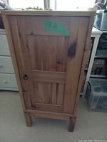Closed front view of the wooden cabinet showing door design and keyhole
