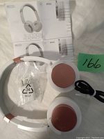 Two pairs of Sentry BT502 Bluetooth headphones with headsets showing one pair with pink ear cups and the other gray. Includes cables and a clear carrying pouch.