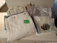 Photo showing folded white waffle weave curtain and other curtains with bagged rings on top