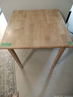 Top view of square wooden kitchen table showing the full surface and minor scratches.