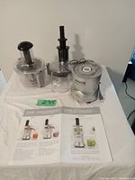 Full view of Veggie Bullet appliance parts including base unit, bowl attachments, pushers, and instruction manuals.