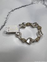Full view of the elastic bracelet showing the white faux pearls and gold-tone accented crystal beads with the brand tag attached.