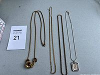 Top view of all five necklaces laid flat showing various chain styles and pendant details.