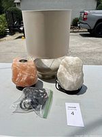 Photo showing two salt lamps, a table lamp with fabric shade and base, and bag with cords.