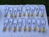 Top-down view of all 18 cable locks arranged in rows, each individually packaged with yellow Master Lock padlocks and keys visible inside clear plastic bags.
