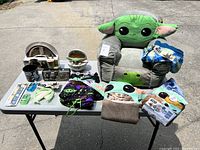 Photo of the full lot laid out on a table including plush chair, pillow, bags, sanitizers, mugs, toothbrushes and boxed items