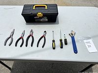 Full view of the toolbox and nine assorted hand tools on a white surface.