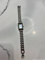 Full view of the Citizen wristwatch showing the two-tone bracelet and rectangular watch face on a white marbled surface.
