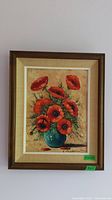 Full view of the framed original oil painting depicting red poppy flowers in a blue vase against a warm beige background, signed by the artist.