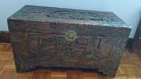 Front view of the cedar chest showing detailed carvings and brass closure.