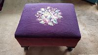 Top view of purple ottoman showing floral cross stitch design in center
