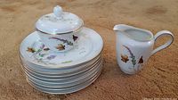 Rosenthal porcelain salad plates stacked with sugar bowl on top and creamer beside them on carpet