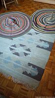 Two 4 ft round multicolor crochet rugs partially on a 6 ft by 4 ft rectangular rug with geometric pattern on floor