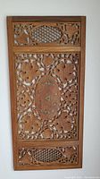 Front view of the rectangular wood wall carving with floral and honeycomb motifs within a wooden frame.