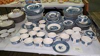 Full view of the assembled Currier and Ives blue transferware set on a table showing plates, cups, saucers, bowls, and serving dishes.