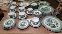 Photo showing full set arrangement: tea cups, saucers, various plates, and bowls all in green Old Curiosity Shop transferware pattern.