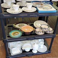 Shelf displaying assorted vintage teacups, luncheon plates with floral designs, small dishes, and decorative bowls across three levels