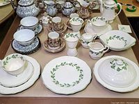 Overview of three tea set designs including white porcelain with green leaf patterns, brown relief antique scene designs, and grey floral patterns on teapots and cups.