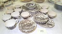 Full view of set including multiple teacups, saucers, bread & butter plates, and dinner plates all in brown Staffordshire Royal Mail transferware ironstone.