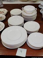 Top-down view of stacks of large dinner plates, medium plates, small bread and butter plates, saucers, and a bouillon cup stacked on top