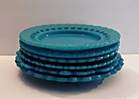 Stack of six blue antique milk glass plates showing thickness and color.