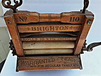 Top view focusing on the wooden frame with printed text and fabric-covered rollers inside the wringer.