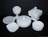 Photo showing the lot of six Fenton hobnail white milk glass items including square candy dish with lid, round candy dish with lid, round candle holder, square dessert bowl, round under plate, footed ivy vase.