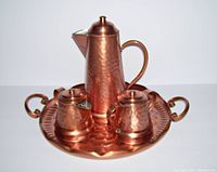Photo of full set arranged on hammered copper tray showing coffee pot, sugar bowl, creamer