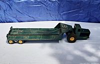 Side view of the vintage vintage Ny-lint TournaHauler flatbed truck showing the green metal body and yellow wheels.
