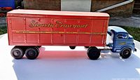 Side view of the vintage Structo Transport metal toy truck showing the blue cab and orange/red trailer with "Structo Transport" branding