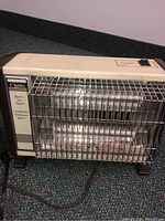 Full view of one heater showing beige plastic body with metal grille and dual quartz tubes visible inside.