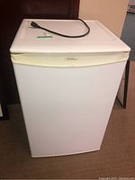 Full view of the white Danby compact fridge exterior with power cord on top.