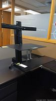Ergotron sit-stand desk attachment assembled and mounted on desk showing side profile and height adjustment feature.