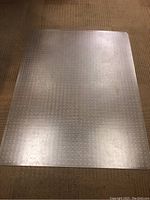 Clear plastic plastic desk mat lying flat on carpet, showing entire shape and size.